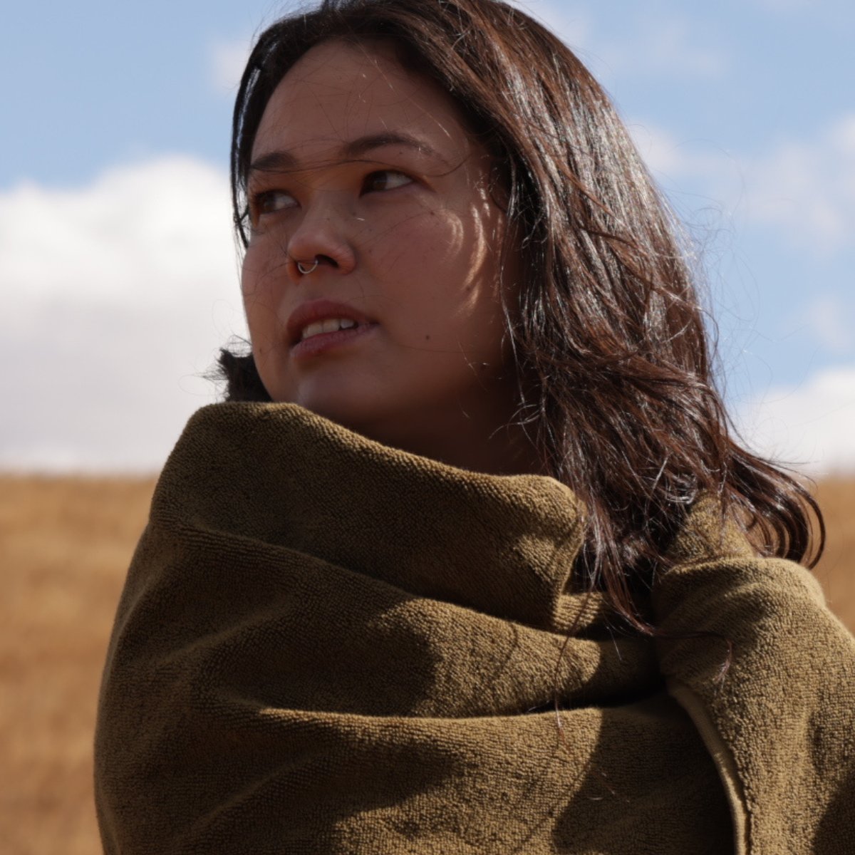 Brunette woman wrapped in khaki towel looking to the left