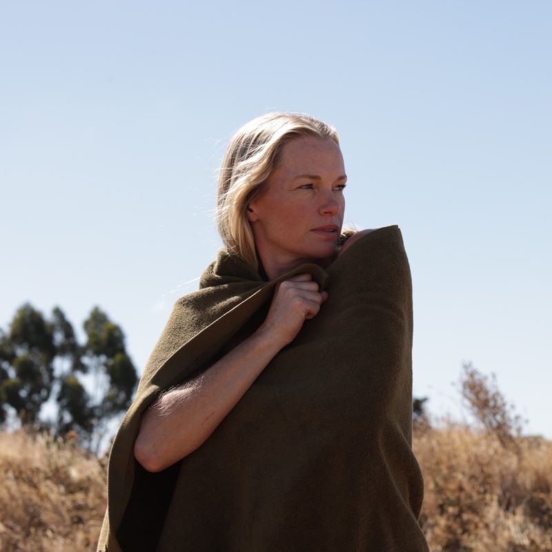 woman with blonde hair wrapped in a khaki towel in a field