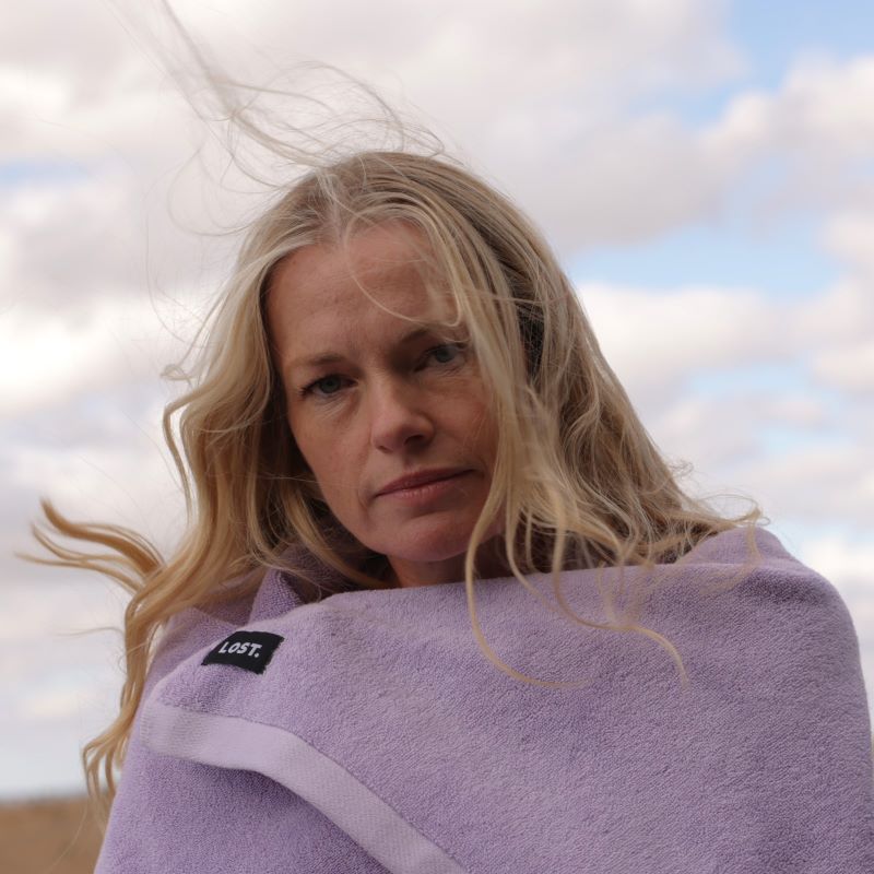 Blonde woman wrapped in lilac bath towel