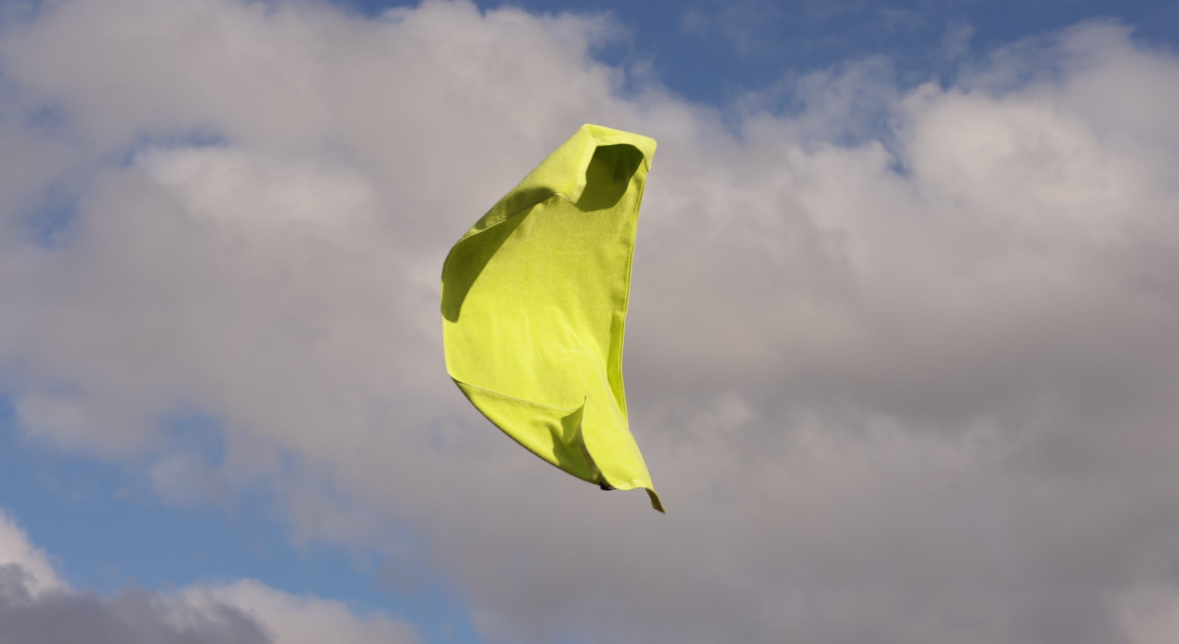 chartreuse bath towel flying against cloudy sky