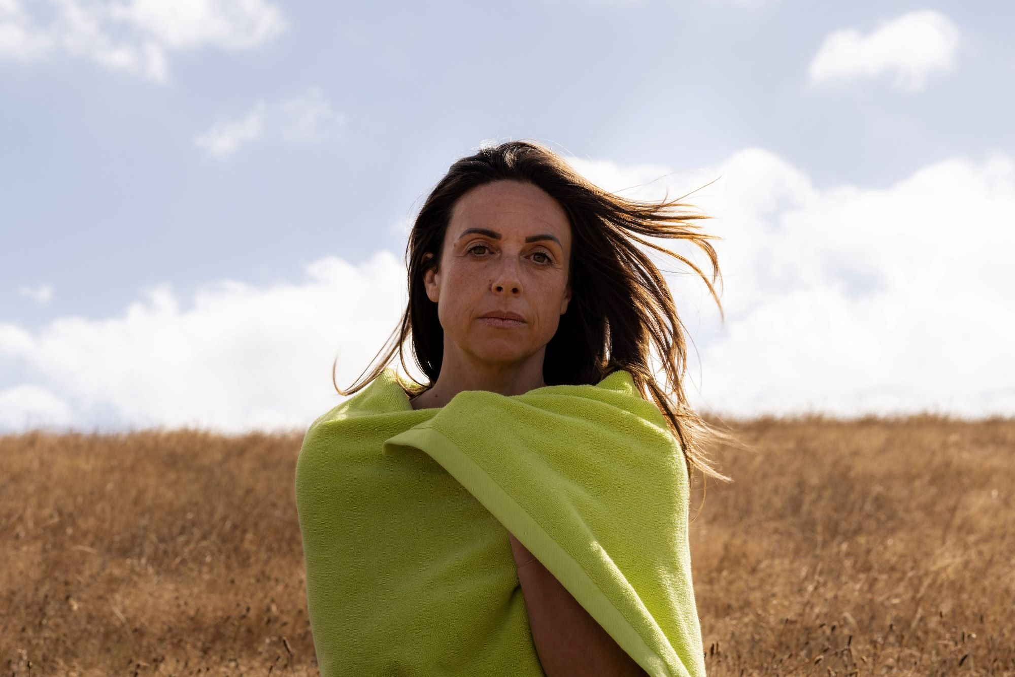 Woman with brown hair wrapped in a chartreuse towel against a blue sky