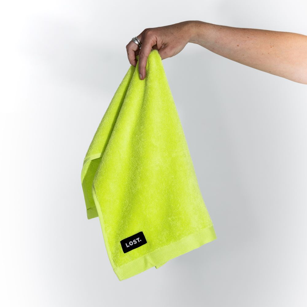 Lost Towels logo on a chartreuse  hand towel held by a woman's hand