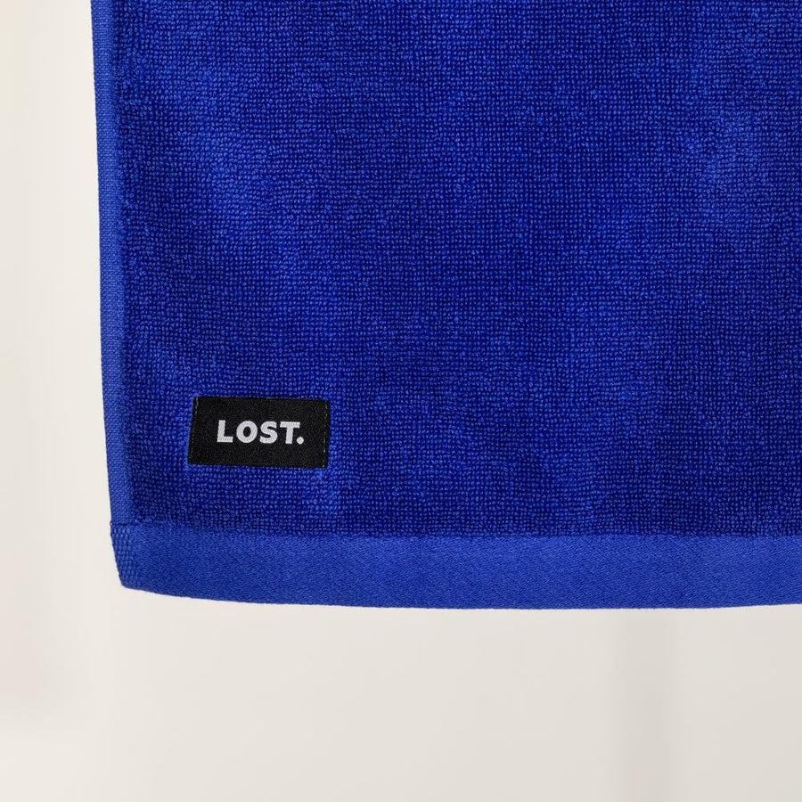 close up of the corner of an electric blue bath towel with a lost label