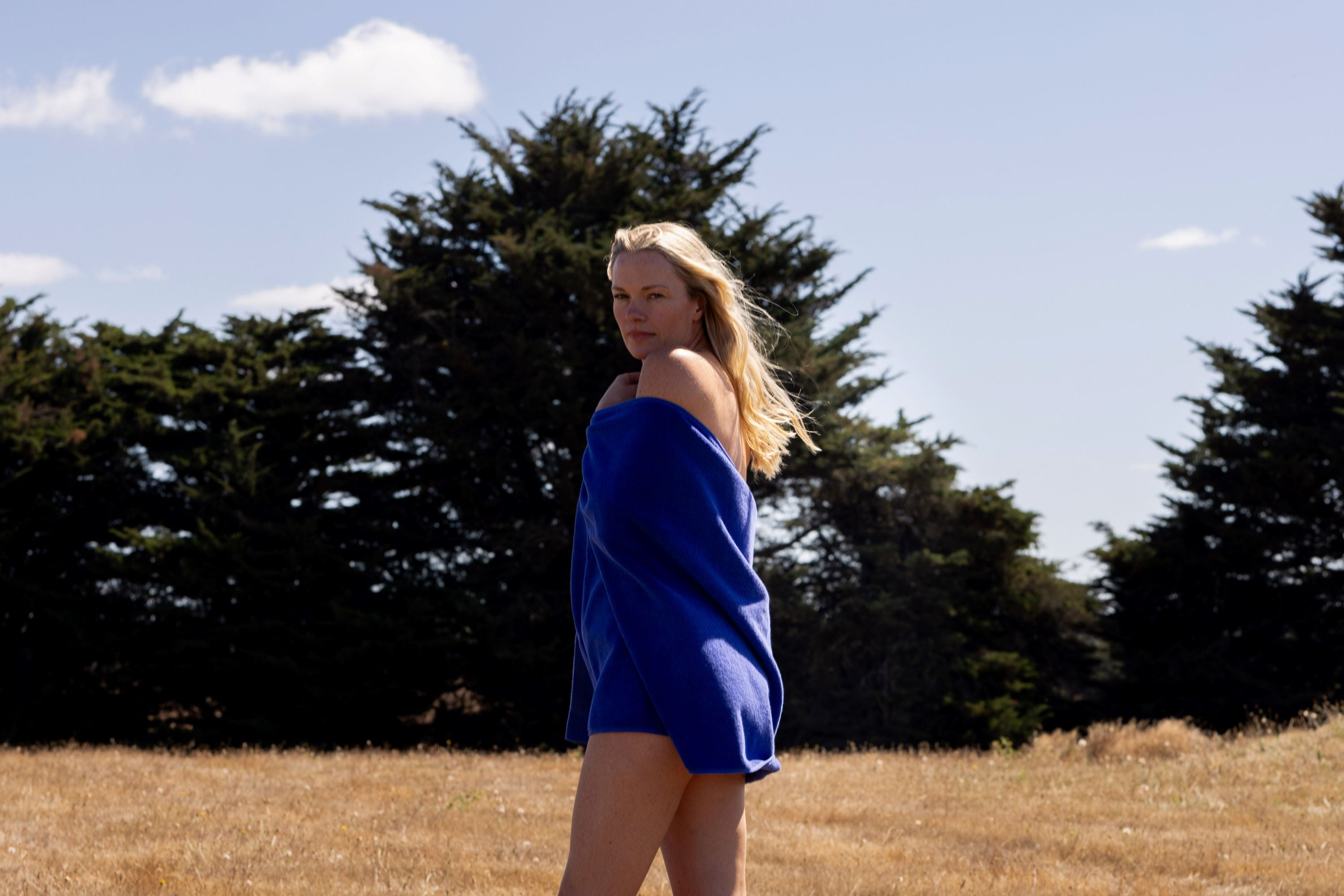 blonde woman wrapped in electric blue bath towel with trees in background