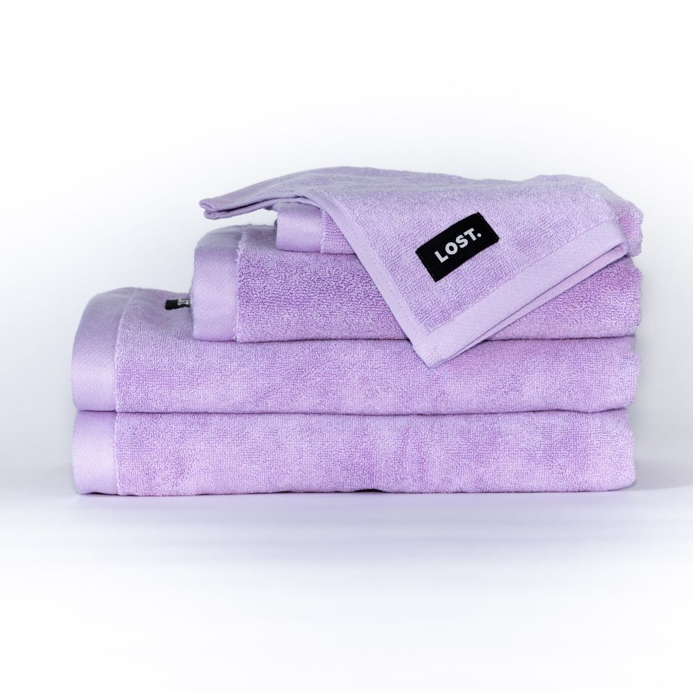 Lost Towels logo on a stack of lilac bath towels