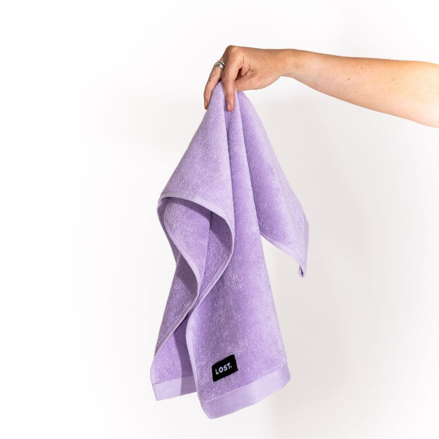 Lost Towels logo on a lilac  hand towel held by a woman's hand