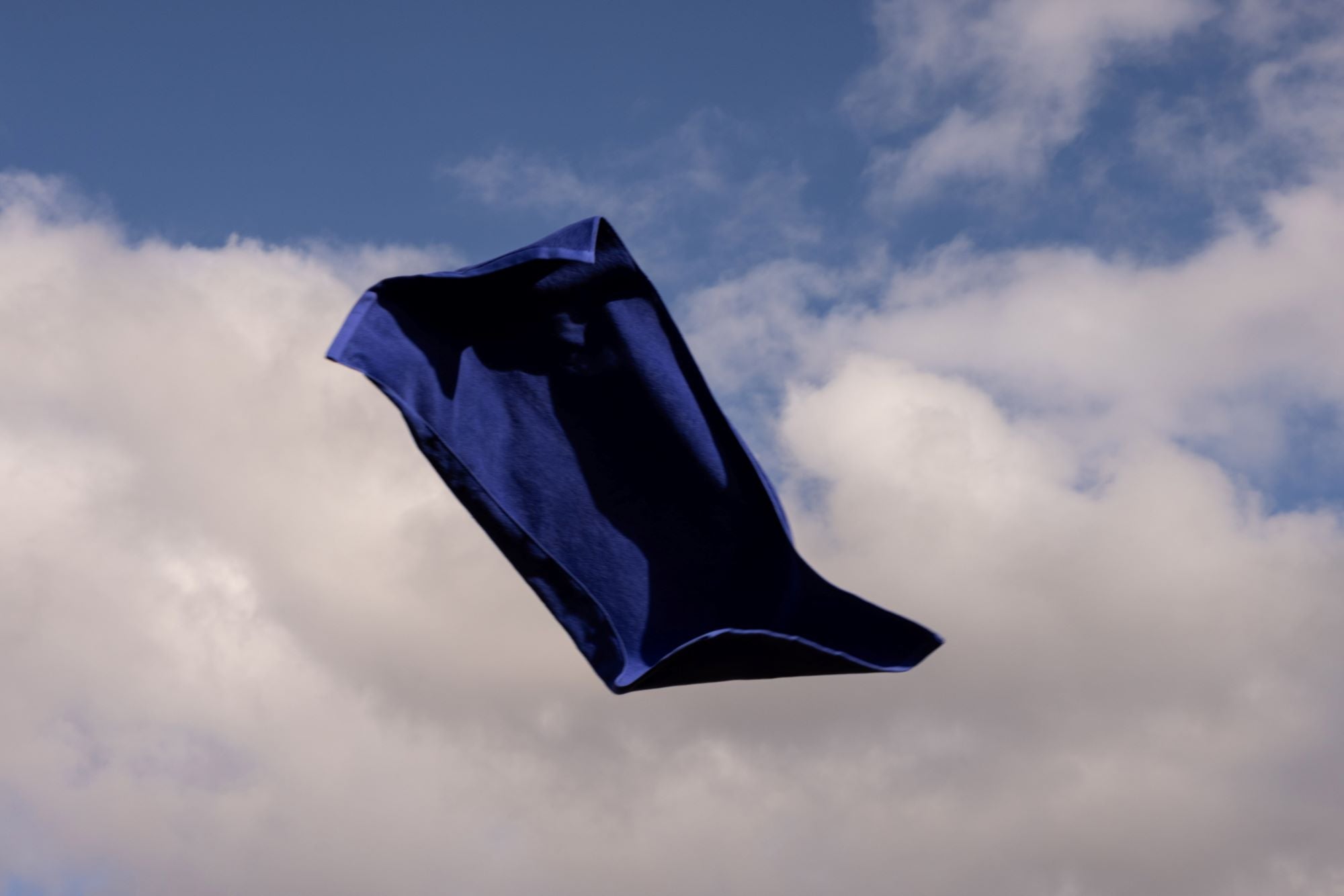 electric blue bath towel flying against cloudy sky