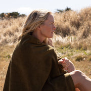 woman with blonde hair wrapped in a khaki bath towel in a field