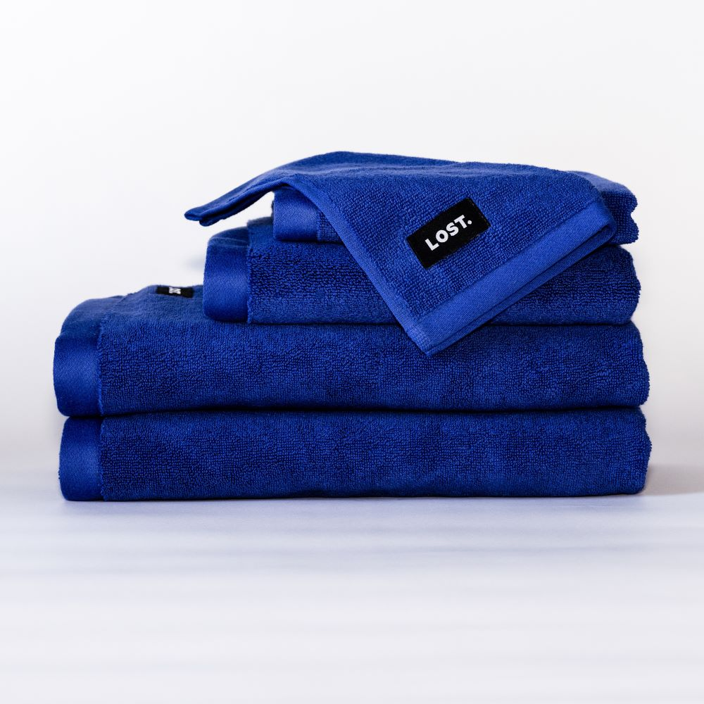 Lost Towels logo on a stack of electric blue bath towels