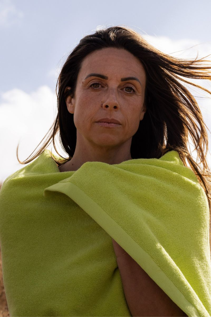 Woman with brown hair wrapped in a chartreuse towel against a blue sky