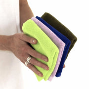 hands holding a chartreuse, lilac, electric blue and khaki face washer