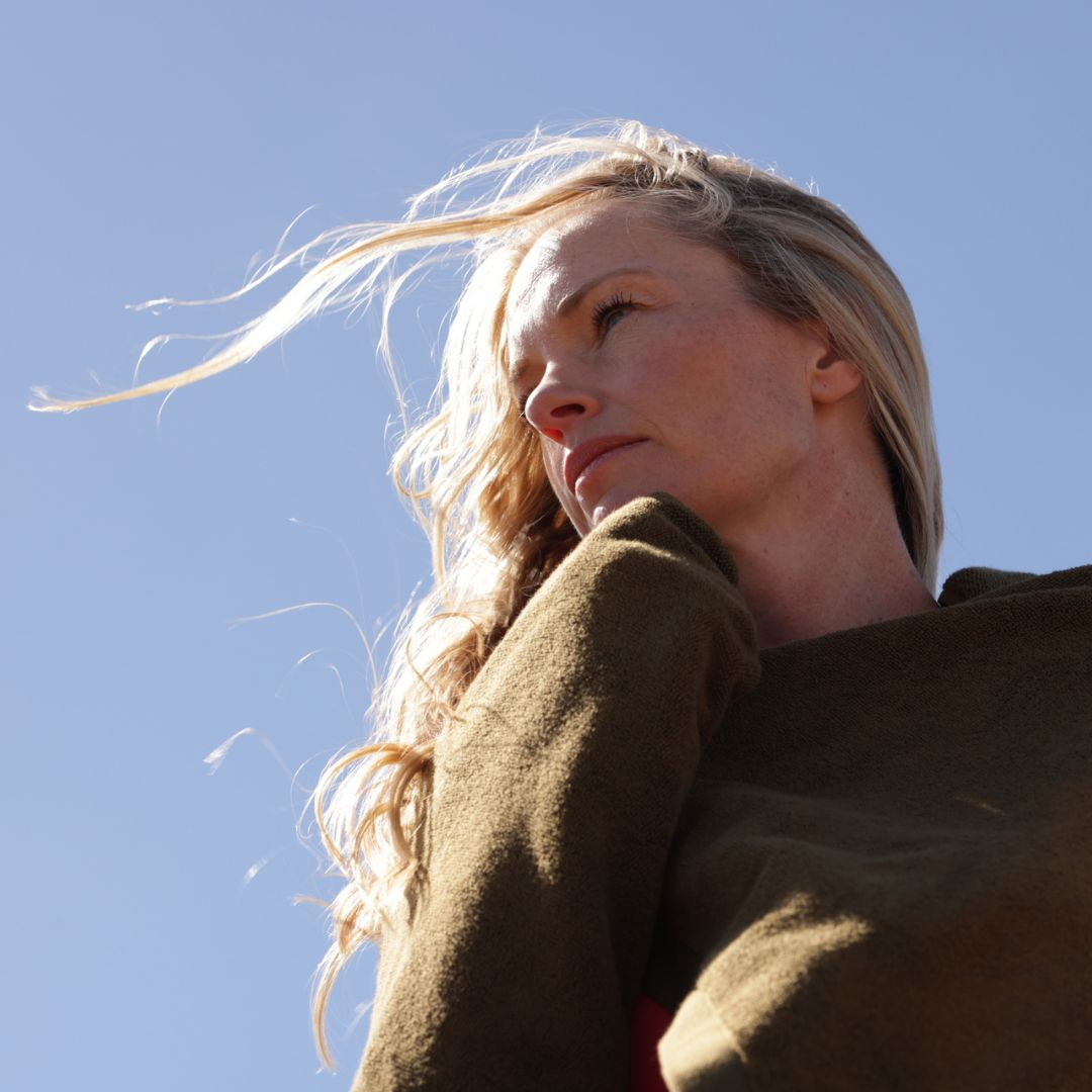 woman with blonde hair blowing in wind in khaki bath towel